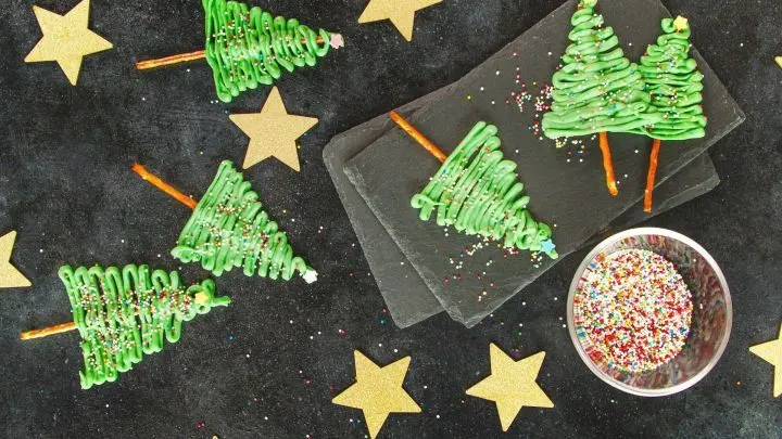 Tannenbäume aus grün-gefärbter Schokolade mit bunten Streuseln dekoriert und Sternchen im Hintergrund.