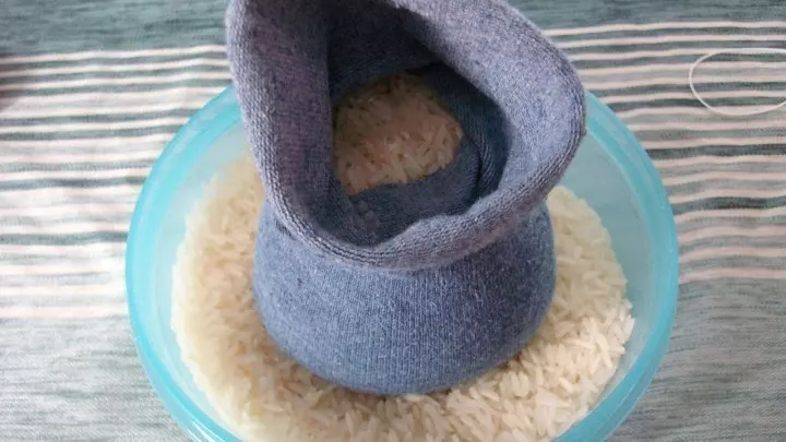 Ins Fußteil der Socke wird viel Reis gefüllt. Es ist viel Reis, damit das auch prall gefüllt ist.