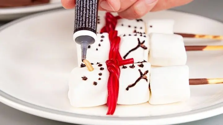 Marshmallows in Schneemann-Form übereinander gesteckt und mit Gesichtern bemalt.