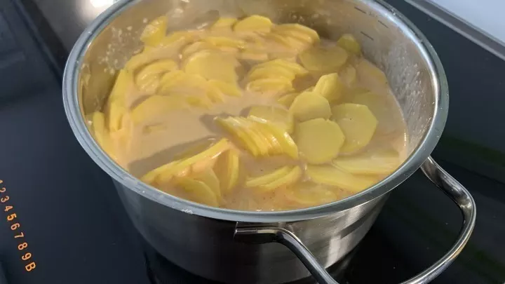 Die Kartoffeln mit einem Hobel in ca. 3 mm dicke Scheiben direkt in die Mischung hobeln, die Kartoffel-Sahne-Milch-Mischung 10 Minuten leicht köcheln lassen.