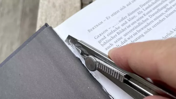 Mit einem Cutter-Messer werden die Seiten aus dem Hardcover-Buch sorgfältig entfernt.
