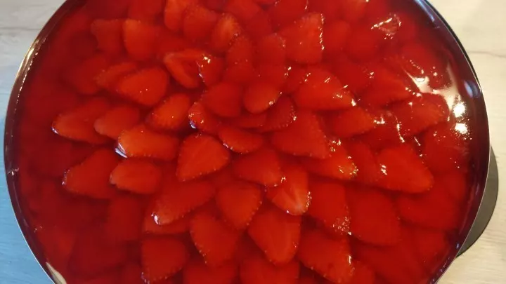 Die Erdbeerscheiben werden wie Dachziegel auf der Torte angerichtet. Danach kommt Tortenguss drauf.