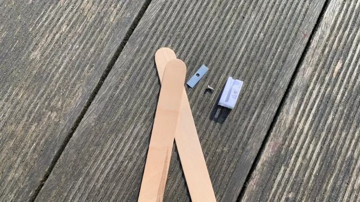 Bauteile für das Mini-Cuttermesser: Zwei Holz-Eisstiele und auseinandergebauter Anspitzer mit kleiner Klinge für das DIY-Projekt.