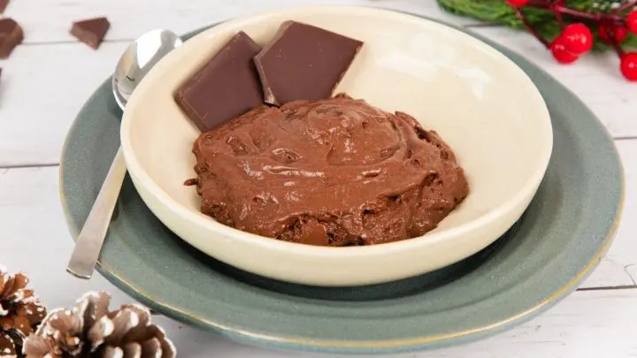 Eine cremige vegane Schokocreme aus zwei Zutaten in einer Sch&uuml;ssel, umgeben von Schokoladentafeln und dekorativem, festlichem Umfeld.