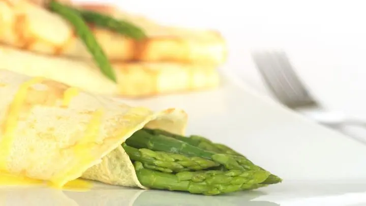 Probiere Spargel im Crêpe-Mantel: Spargel und Schinken in zarten Crêpes, gekrönt mit köstlicher Sauce Hollandaise.