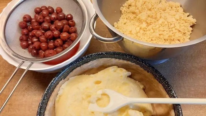 Hier sieht man folgende Zutaten: die fertigen Streusel, den eingepassten Kuchenboden, die Puddingmasse und die Kirschen.