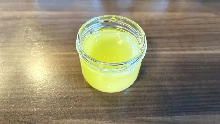 Ein Glas mit selbstgemachter Handcreme steht auf einem hölzernen Tisch.