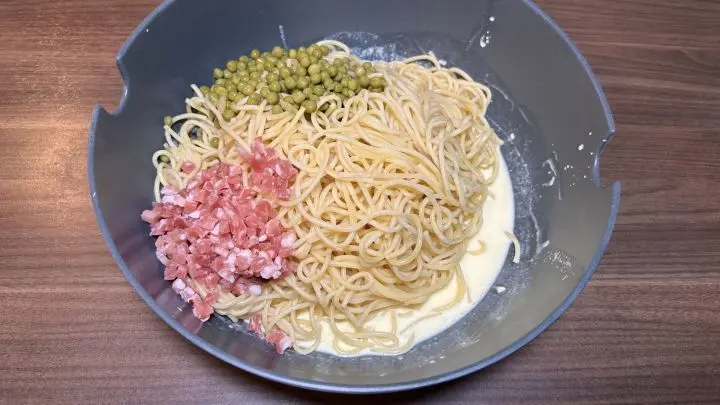 Zu der Sahnemasse dürfen jetzt alle anderen Zutaten hineinhüpfen: Spaghetti, Erbsen und Schinkenwürfel.