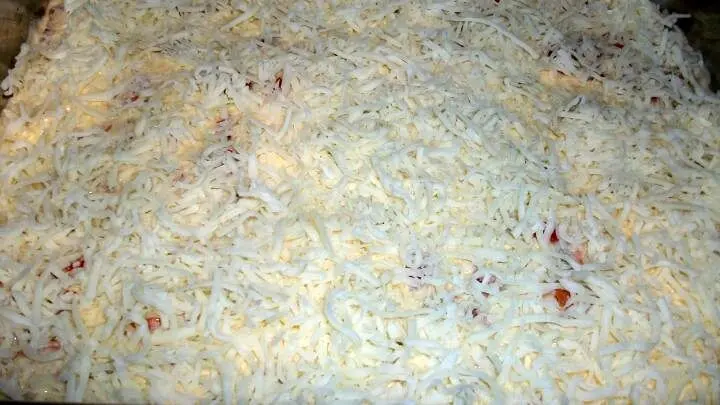 Dann den Frischkäse mit Sahne, Eier und Gewürzen gut verrühren und über den Auflauf verteilen. Danach gleichmäßig Käse darüber streuen.