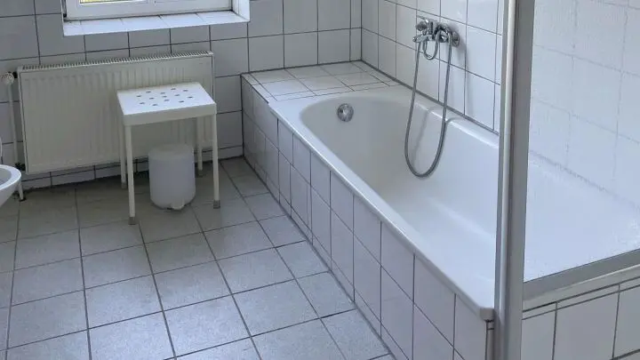 Dieselbe Badewanne, nachdem sie mit Zementschleier-Entferner und einem rauen Schwamm behandelt wurde.
