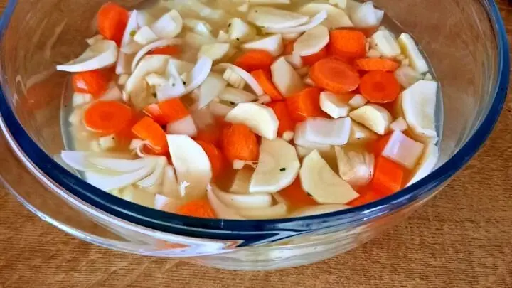 Wasser und Reis, sowie kleingeschnittenes Wurzelgemüse und Gewürze bilden die Unterlage für das Fleisch. Frisches Gemüse in Brühe als Basis für das Hähnchen-Reisbett – so startest du das leckere Ofengericht, dazu gibt es Feldsalat und Avocado.