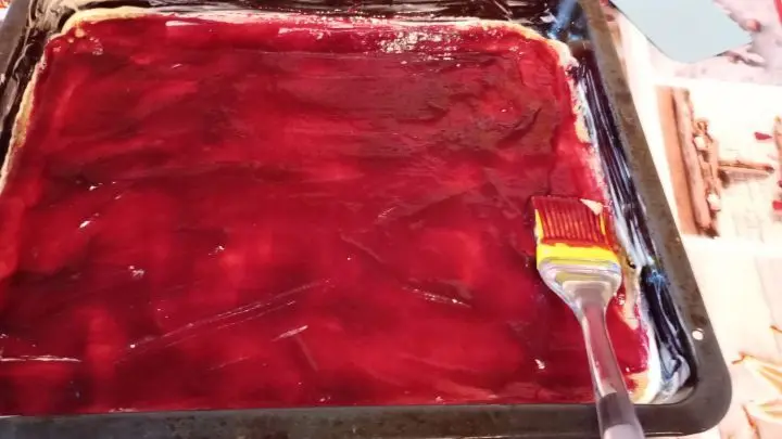 Wenn der Teig ausgerollt ist, wird er mit der Marmelade gleichmäßig bestrichen. Wenn der Teig ausgerollt ist, wird er mit der Marmelade gleichmäßig bestrichen.