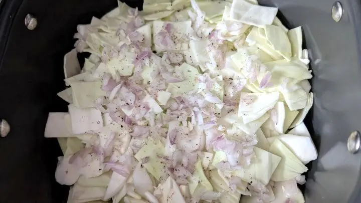 One-Pot-Kohlrouladen: Im Topf liegen geschnittener Kohl und Zwiebeln, schon gew&uuml;rzt &ndash; die Basis f&uuml;r das schnelle Rouladen-Gericht.