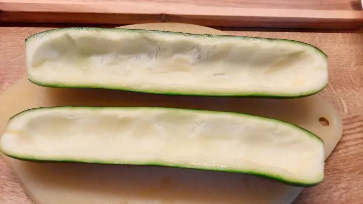 Die mittelgro&szlig;e Zucchini wird mit einem L&ouml;ffel ausgeh&ouml;hlt und das Fruchtfleisch wird f&uuml;r die F&uuml;llung verwertet.