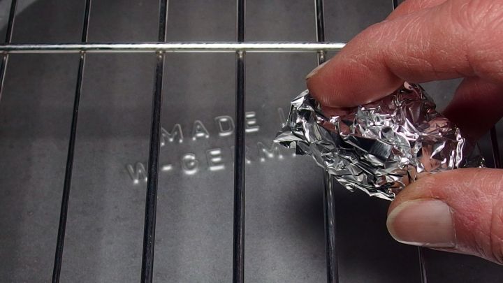 Mit zusammengeknüllter Alufolie den Grillrost säubern.