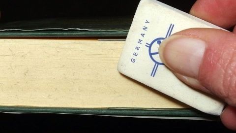 Fingerabdrücke und andere Schmutzspuren auf dem Schnitt eines Buches mit einem Radiergummi, und wenn das nicht hilft, mit feinem Schmirgelpapier entfernen.