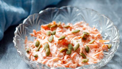 Der leckere Möhrensalat wird mit einem geriebenen Apfel und Kürbiskernen verfeinert. Die Soße besteht aus fettarmen Joghurt sowie Kürbiskernöl.