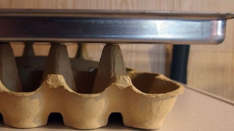 Zwei leere Eierkartons aus Pappe helfen beim Auskühlen von Plätzchen auf dem Backblech.