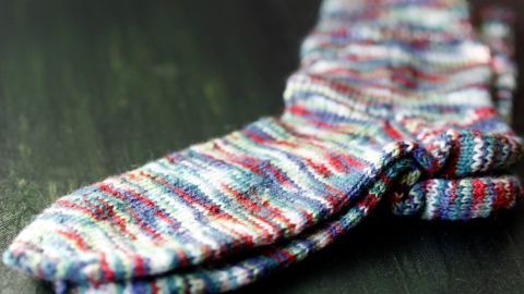 Man nimmt die anzuschlagenden Maschen mit einem Hilfsfaden auf (oder aus einer gehäkelten Schnur) und strickt nach 2 gleichen glatten Maschen gleich die (Kappen-)Ferse. Dann den Socken stricken bis zur gewünschten Größe.