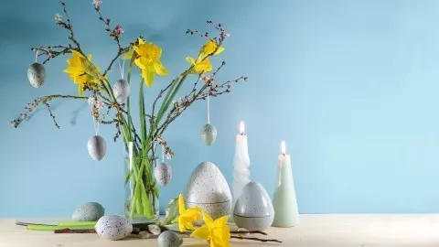 Zweige und Narzissen in einer Vase arrangiert, mit Ostereiern. Narzissen sollten etwas später hinzugefügt werden, da sie einen Schleim absondern, der andere Blumen schneller welken lassen.