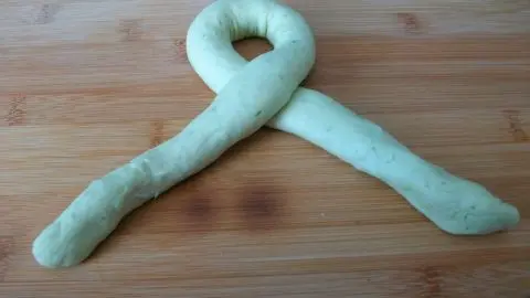 Hier siehst du den ersten Schritt auf dem Weg zum fertigen Brötchen: Forme aus einem Teigstrang eine Schlaufe.