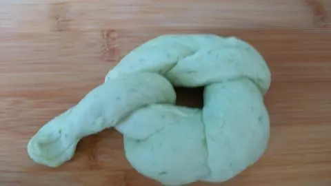 Der Strang wird noch weiter um den Kringel gewickelt. Der Teigling auf dem Bild zeigt den Knoten, bevor er gebacken wird.