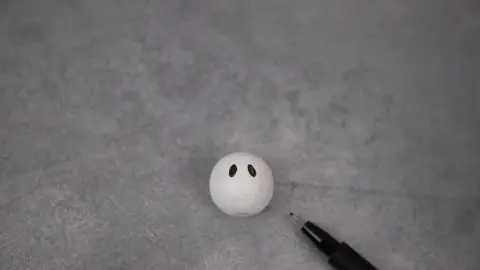 Inzwischen ist die weiße Farbe bestimmt getrocknet und du kannst mit einem Fineliner ein schauriges Gesicht auf die Holzkugel malen.