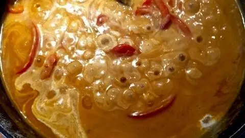 Puten-Curry: In der Pfanne k&ouml;chelt eine cremige Currysauce mit Paprikastreifen &ndash; so wird das Gericht sch&ouml;n s&auml;mig.