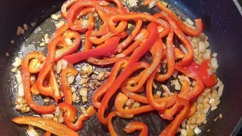 F&uuml;r das Rezept Puten-Curry: Paprikastreifen und Zwiebeln werden in der Pfanne angebraten &ndash; die aromatische Basis f&uuml;r die Curryso&szlig;e.