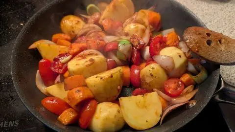 Schinkenbraten auf Kartoffel-Gemüsebett: Braten herausgenommen und das Gemüse in die Pfanne gegeben mit allen Gewürzen. Zum Rezept Schinkenbraten auf Kartoffel-Gemüsebett: In der Pfanne braten Kartoffeln, Möhren, Zwiebeln und Tomaten als würzige Beilage.