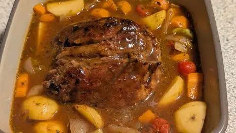 Schinkenbraten auf Gemüsebett: Das Gemüse mit dem Portwein & der Brühe abgelöscht & in die Form gegeben. Braten obenauf legen. Wie im Artikel Schinkenbraten auf Kartoffel-Gemüsebett: saftiger Braten in der Form, umgeben von Kartoffeln, Möhren und kräftiger Soße.