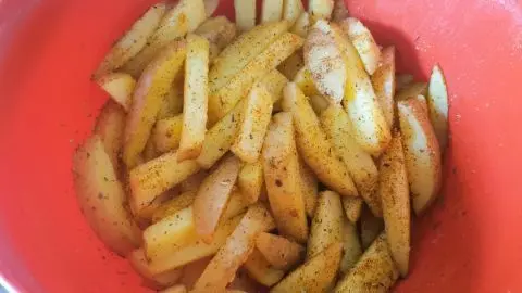 Im Tipp Einfache Steakhouse-Fries mit Schale siehst Du gew&uuml;rzte Kartoffelstifte in der Sch&uuml;ssel &ndash; bereit f&uuml;r Ofen oder Fritteuse.