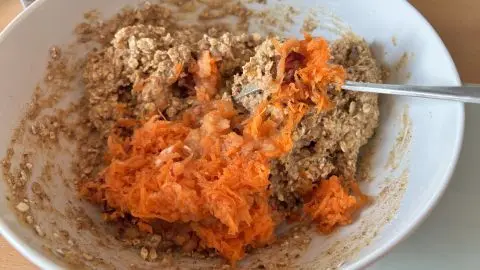 Den geriebnen Apfel und die geriebene Karotten unter den Teig heben. Die beiden machen die Kekse extra saftig. Teigschüssel für Buchweizen-Haferflocken-Kekse ohne Zucker: geriebene Möhre und Haferflocken als Basis für gesunde, einfache Plätzchen