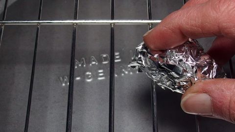Mit zusammengeknüllter Alufolie den Grillrost säubern.