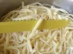Einzelnes Spaghetti zur Garprobe aus dem Wasser heben