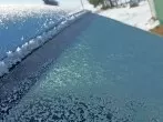 Gefrorene Autoscheibe mit lauwarmem Wasser enteisen
