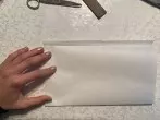 Einen Bogen Butterbrotpapier hochkant hinlegen und die untere Hälfte nach oben falten. Dabei ist es wichtig, dass die hintere Hälfte 1 cm herausschaut. 