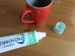Getrocknete Kaffeeränder auf dem Tisch mit Zahnpasta entfernen