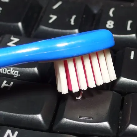 PC-Tastatur mit leicht feuchter Zahnbürste reinigen