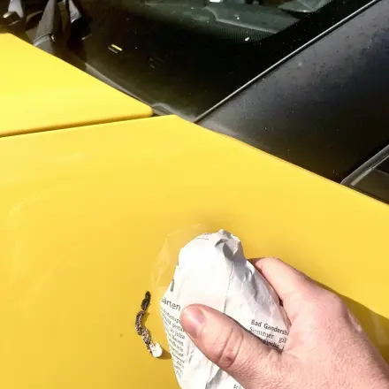Vogelkacke auf/am Auto mit einem nassen Pack Zeitungspapier entfernen