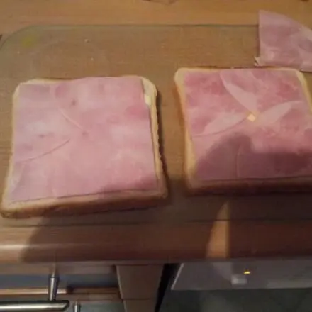 Runde Wurst- oder Schinkenscheiben auf eckigem Toast verteilen