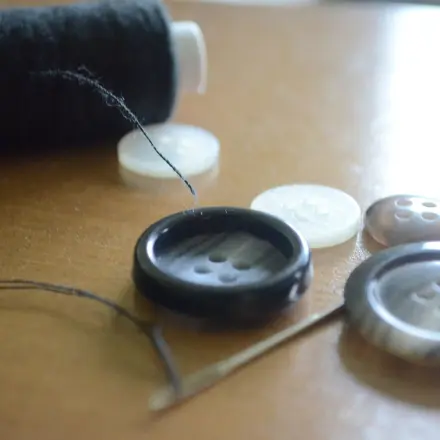 Knopf mit vier Knopflöchern annähen