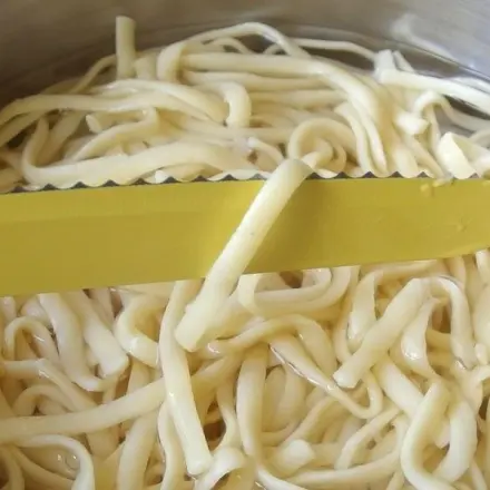 Einzelnes Spaghetti zur Garprobe aus dem Wasser heben
