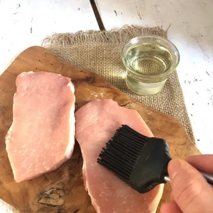 Unpanierte Schnitzel mit dem Pinsel mit Öl bestreichen