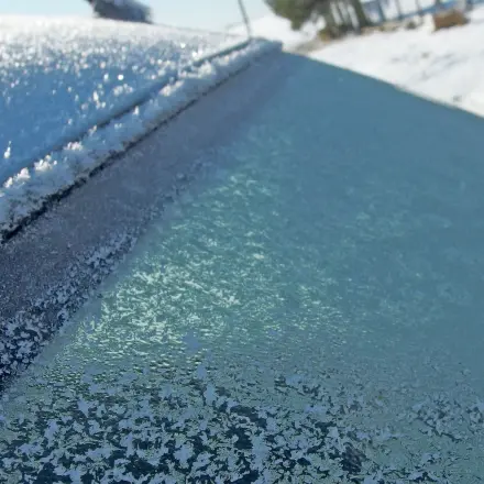 Gefrorene Autoscheibe mit lauwarmem Wasser enteisen