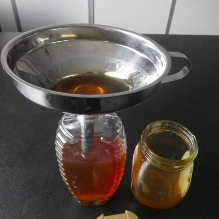 Honig aus dem Glas in vorhandene leere Flotte Biene umfüllen