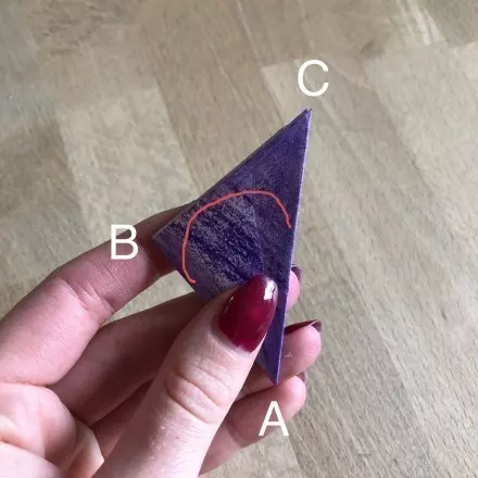 Hat man ein Quadrat zu einem kleinen Dreieck gefaltet, muss man nun Spitze C herausschneiden, sodass auch Spitze B abgerundet wird.