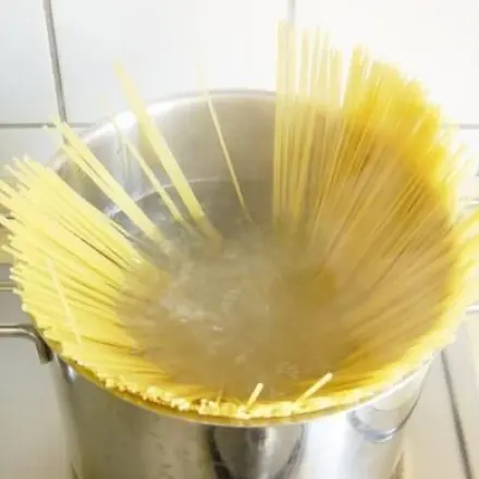 Spaghetti geschickt in den Topf geben