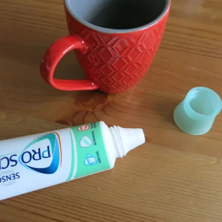 Getrocknete Kaffeeränder auf dem Tisch mit Zahnpasta entfernen