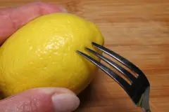 Nur ein paar Tropfen Zitronensaft - Zitrone mit Gabel anstechen